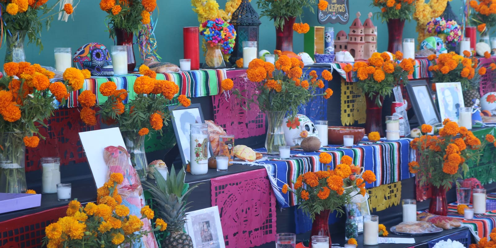 A Día de los Muertos ofrenda covered in marigolds, candles and papel picado